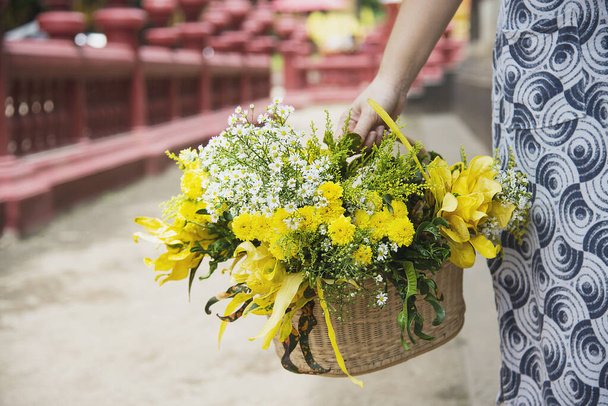 Dame asiatique tenant panier de fleurs jaunes fraîches pour la participation cérémonie bouddhiste traditionnelle locale personnes avec concept de relation de religion
 - Photo, image