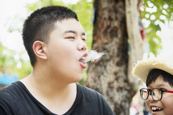 Asian boy eating smoking canny happily - people and snack happy time concept - Foto, Imagem