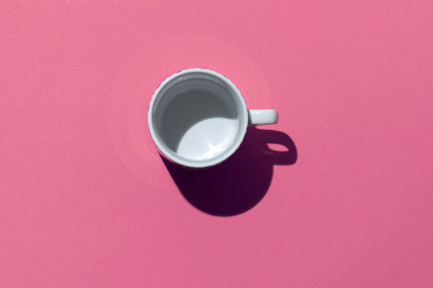 Taza de té vacía sobre fondo de papel rosa. Taza de café de arriba. Concepto mínimo Sombra profunda dura. Piso tendido, vista superior
. - Foto, Imagen