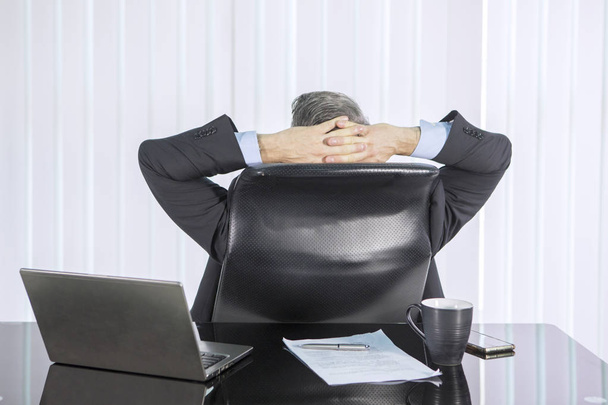 Achteraanzicht van zakenman ontspannen in kantoor - Foto, afbeelding