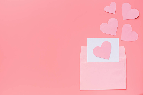 Valentine's day background. greeting card with pink hearth in envelope. Flat lay, top view, mockup, template, copy space. Minimal abstract composition for 14 February celebration - Photo, Image