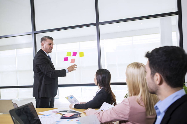 Caucasian business manager using sticky notes on glass wall - Foto, imagen