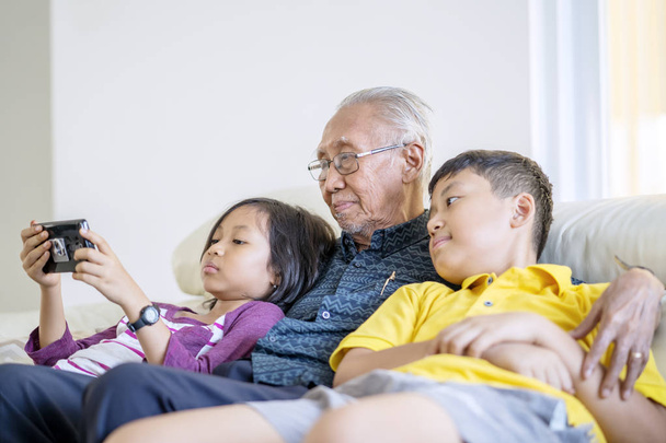 grandfather and grandchildren watching a movie - 写真・画像