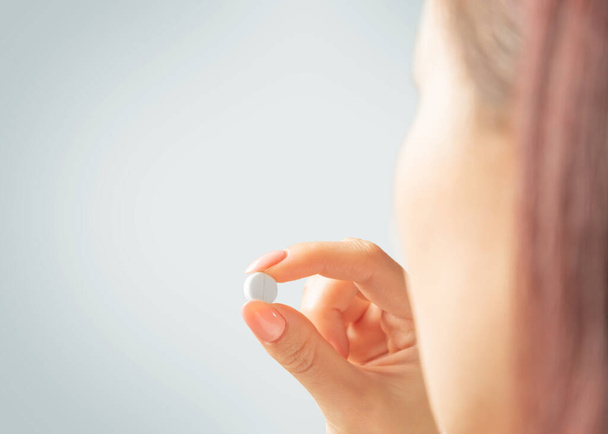 Woman holding a medication tablet or vitamin. - Foto, afbeelding