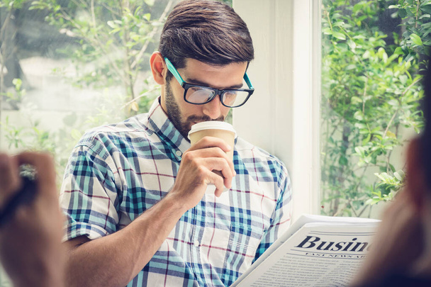 Jonge casual zakenman leest zakelijk nieuws in de ochtend op - Foto, afbeelding