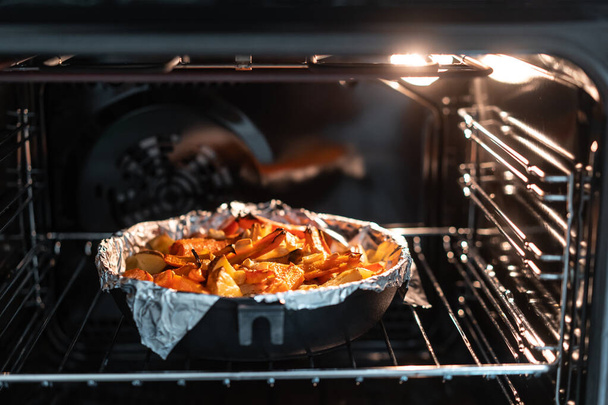 Baked potatoes with carrot and other spices in roasting pan. - Foto, Bild