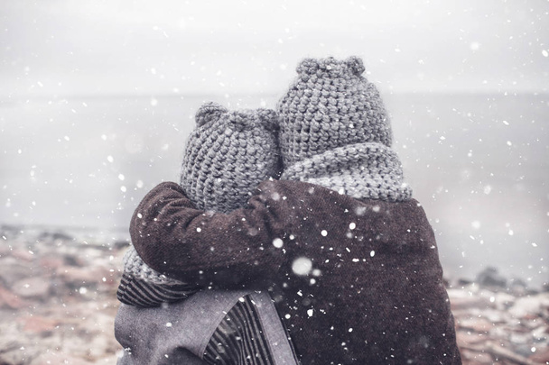 Chica de punto sombrero gris abrazando a su hermano pequeño congelado
 - Foto, imagen