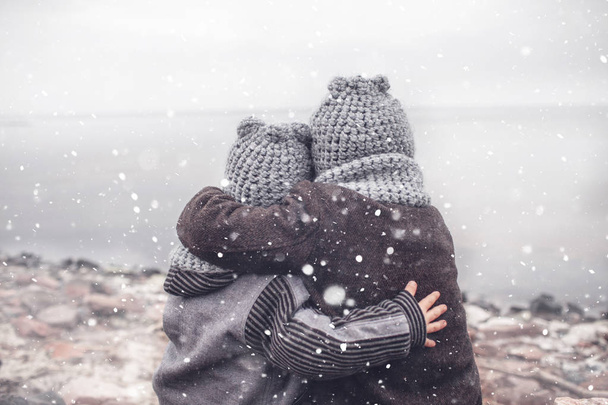 Ragazza in maglia cappello grigio abbracciando il suo fratello più piccolo congelato
 - Foto, immagini