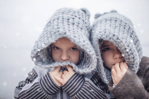 Girl in knitted grey hat hugging her frozen smaller brother - Photo, Image