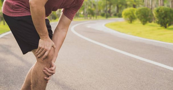 Травми коліна. Молодий спортивний чоловік тримає коліно руками в па
 - Фото, зображення