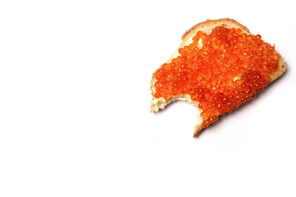Bitten sandwich with butter and red caviar on a white background - Фото, зображення