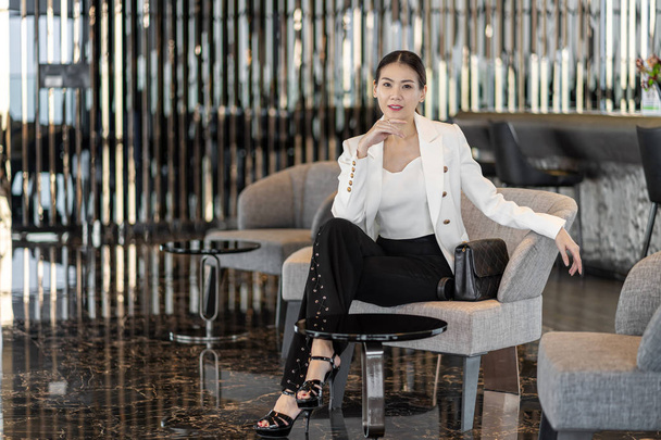 Retrato Mujer de negocios asiática vestida con traje formal sentada en el sofá en el vestíbulo moderno, oficina o espacio de coworking, café descanso ocio, moda y estilo de vida después del tiempo de trabajo, concepto de gente de negocios
 - Foto, imagen