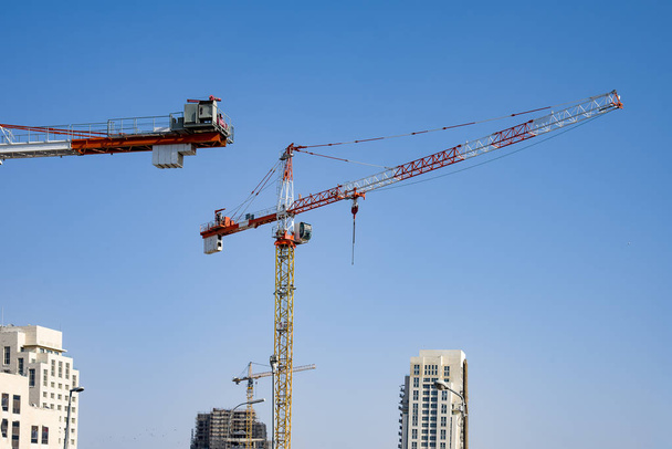 Lugar de construcción con grúas, construcción de un edificio de gran altura sobre fondo azul del cielo
 - Foto, imagen