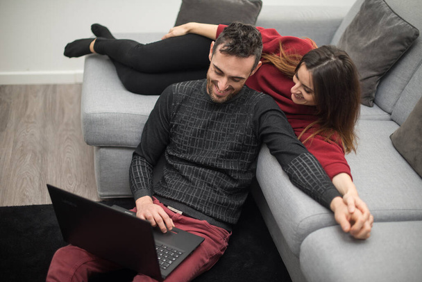 Retrato de um casal feliz usando um computador portátil em sua casa - Foto, Imagem