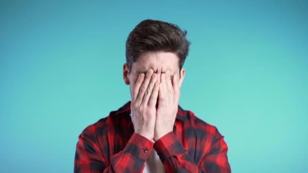 Young guy covers his face with hands from fatal disappointment, failure. Depressed lost man in red plaid shirt. Drama, emotions concept - Video