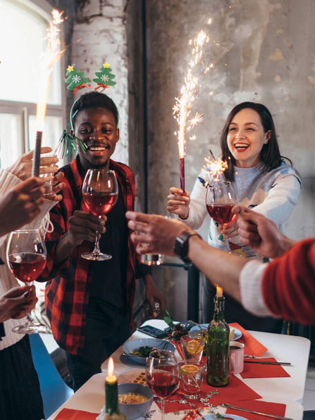 Grupo de amigos brindando bebidas en una fiesta. Personas tomando vino en el interior en unas vacaciones de invierno
 - Foto, imagen