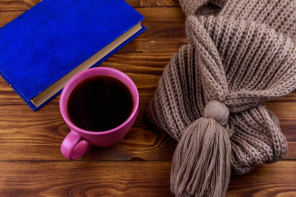 Cup of coffee, knitted scarf and book on wooden background - Foto, immagini
