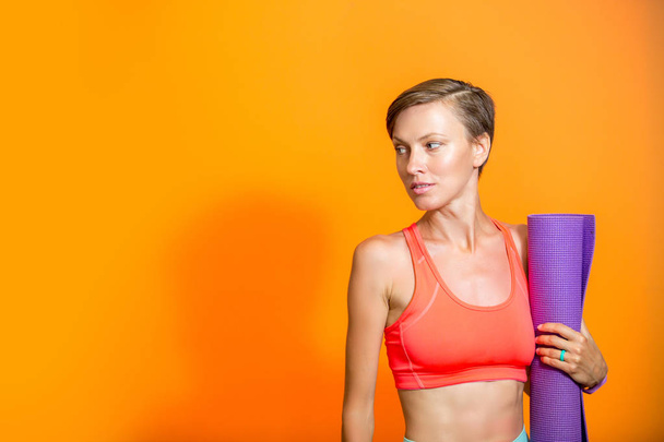  Sporty yoga girl with yoga mat isolated over yellow orange background, copy space - Foto, immagini