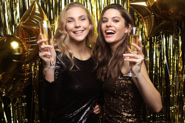 Hermosas chicas celebrando el Año Nuevo. Preciosas mujeres jóvenes sonrientes disfrutando de la celebración de la fiesta, divirtiéndose juntas
. - Foto, Imagen