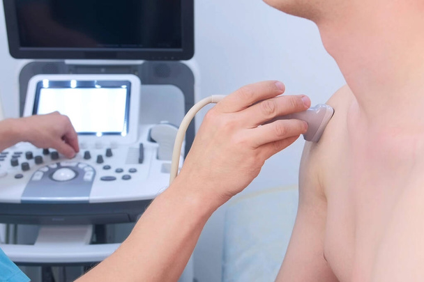 Doctor makes ultrasound of shoulder joint man using ultrasound scanner, closeup. - Foto, Imagen