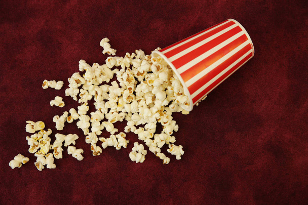 Popcorn im Pappbecher und Popcorn auf rotem Hintergrund mit Platz für Text und Bild. flache Lage, Draufsicht. Hintergrund, Muster, Karte. Kinokonzept. - Foto, Bild