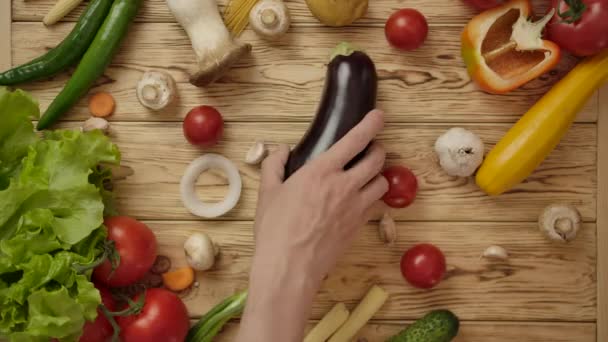 Gesichtsloser Koch nimmt Auberginen vom Holztisch - Filmmaterial, Video
