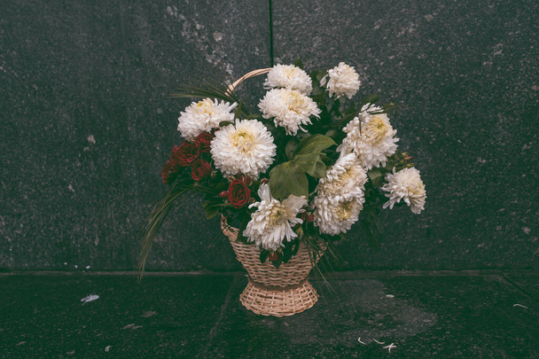 Flowers on the monuments, a lonely bouquet of flowers stands on the street, on a black background - 写真・画像