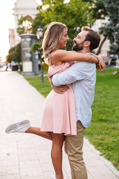 Loving couple walking by street outdoors hugging - Фото, изображение