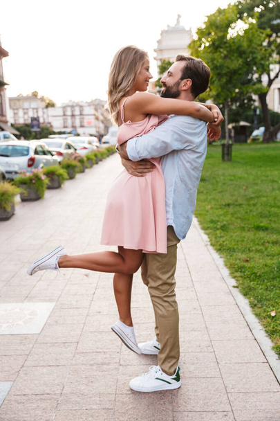 Loving couple walking by street outdoors hugging - Фото, зображення