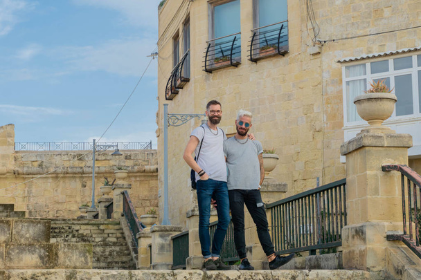 Homoseksuele mannen paar poseren voor foto met plezier in middeleeuwse smalle straat in Birgu, stad van Malta - Foto, afbeelding