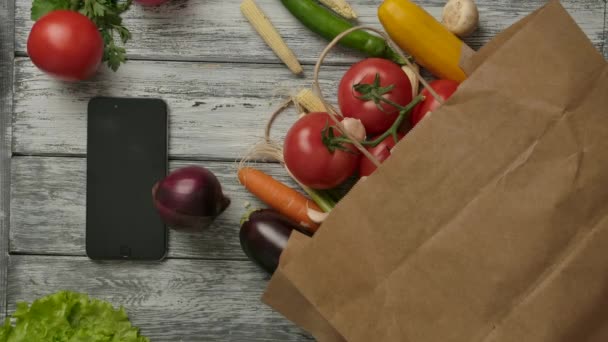 Vegetables spinning near smartphone and groceries - Video, Çekim
