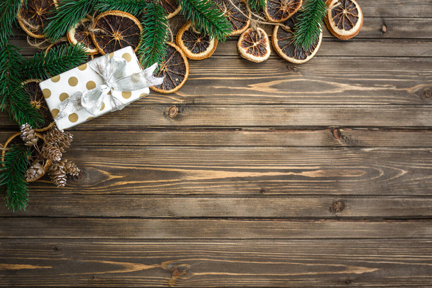 Christmas background with decorations, gift box and mandarins on wooden board. Copy space - 写真・画像