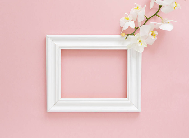 White photo frame with white orchids on the pink background. Beautiful White Phalaenopsis orchid flowers, wooden white photo frame. Women's Day, Flower Card. Valentine's day. Flat lay, top view, copy space.     - Zdjęcie, obraz