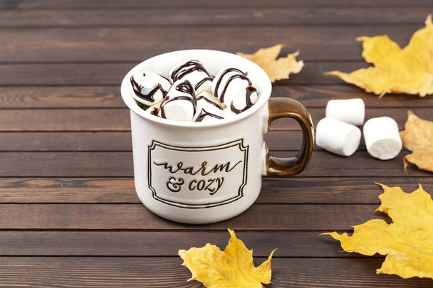 Hot cocoa with marshmallows in a ceramic mug on a wooden table. The concept of a cozy holiday. - Photo, Image
