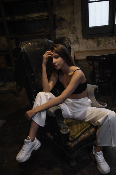 Dziewczyna brunetka siedzi troskliwie na krześle - Zdjęcie, obraz