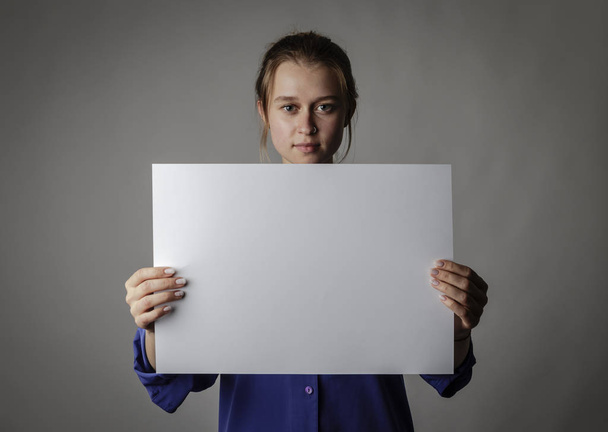Young woman in blue is holding white paper. - Fotografie, Obrázek