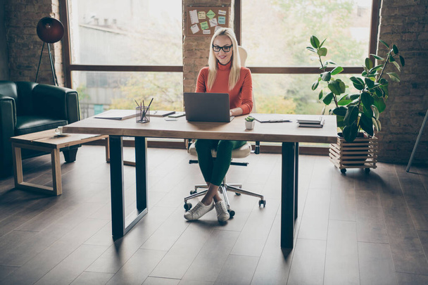 Full size photo of positive woman worker sit table use laptop work on start-up strategy type wear red turtleneck in office loft - Valokuva, kuva