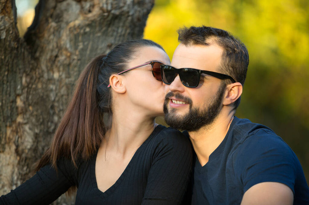 Portret van een man en een vrouw met een zonnebril in het bos. Jonge stijlvolle echtpaar op de achtergrond van de natuur. Warme herfstavond in het bos. - Foto, afbeelding