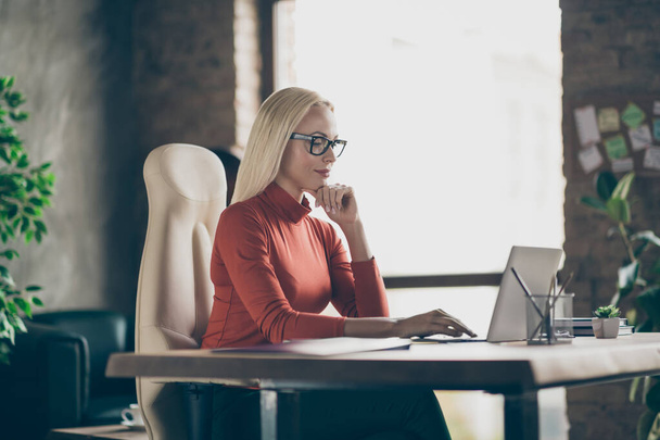 Photo of serious confident pensive woman looking into laptop comparing annual income for previous year with current one wearing spectacles - Foto, immagini