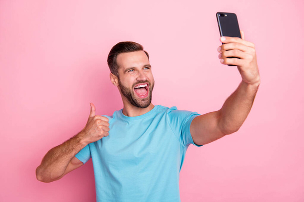 Photo of casual cheerful screaming man shouting into telephone speaking by video call recommending travel place to visit by showing thumb up isolated pastel color background - Foto, Imagem