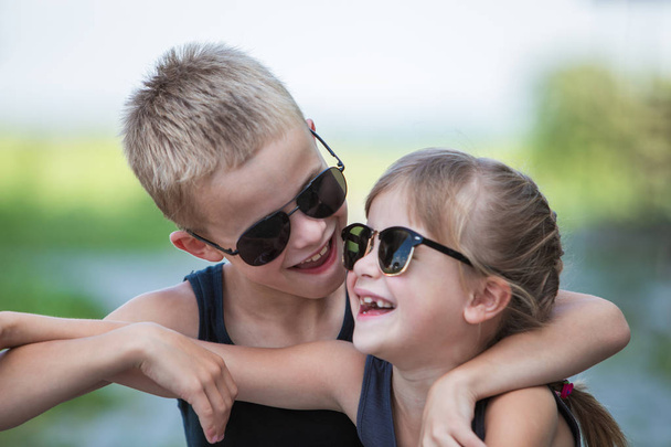 Two children in black sunglasses having fun time outdoors in sum - 写真・画像