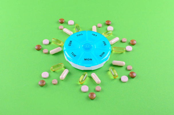 különböző táplálék-kiegészítőket egy hétig, és a tabletták doboz zöld háttér - Fotó, kép