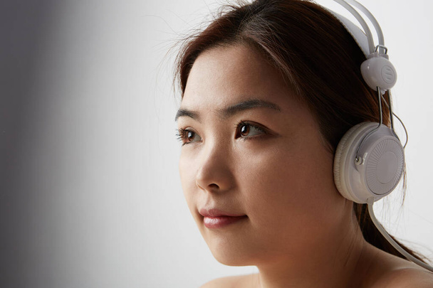 Portrait of Chinese woman posing on the white background with big earphones. Isolated. - Fotografie, Obrázek