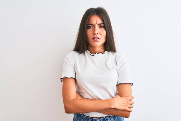 Young beautiful woman wearing casual t-shirt standing over isolated white background skeptic and nervous, disapproving expression on face with crossed arms. Negative person. - Zdjęcie, obraz