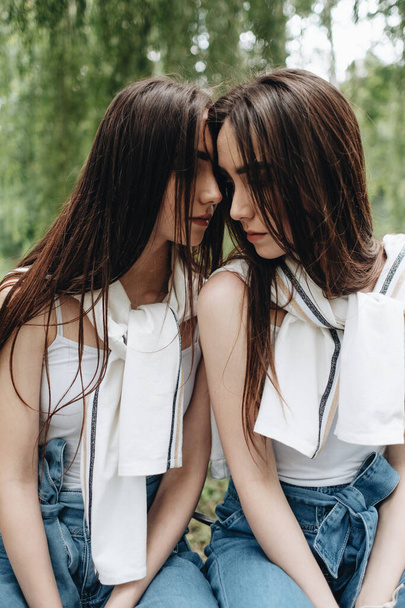 Porträt von zwei brünetten Zwillingsschwestern in Jeans und weißem T-Shirt, beste Freundinnen für immer - Foto, Bild
