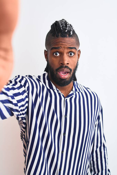 Africano americano homem com tranças fazer selfie por câmera sobre isolado fundo branco assustado em choque com um rosto surpresa, com medo e animado com expressão de medo
 - Foto, Imagem