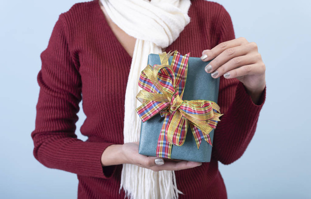 women hand holding green gift box on blue background for christmas and new year concept. - 写真・画像