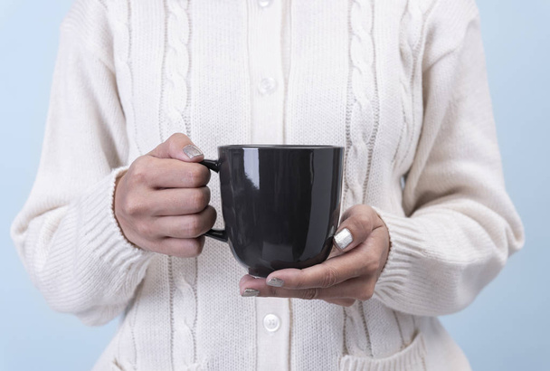 жіноча рука тримає чорну керамічну чашку кави. макет для креативної реклами текстового повідомлення або рекламного контенту
. - Фото, зображення