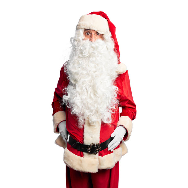 Hombre guapo de mediana edad con traje de Papá Noel y barba de pie En la cara de choque, mirando escéptico y sarcástico, sorprendido con la boca abierta
 - Foto, Imagen