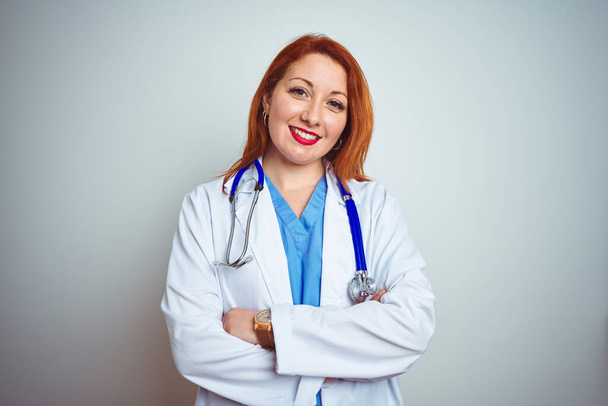 Young redhead doctor woman using stethoscope over white isolated background happy face smiling with crossed arms looking at the camera. Positive person. - Photo, image